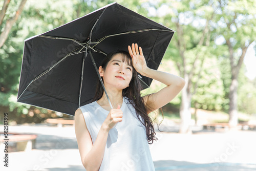 夏に熱中症対策・紫外線対策のため日傘をさすアジア人女性（体調不良・汗）
 photo