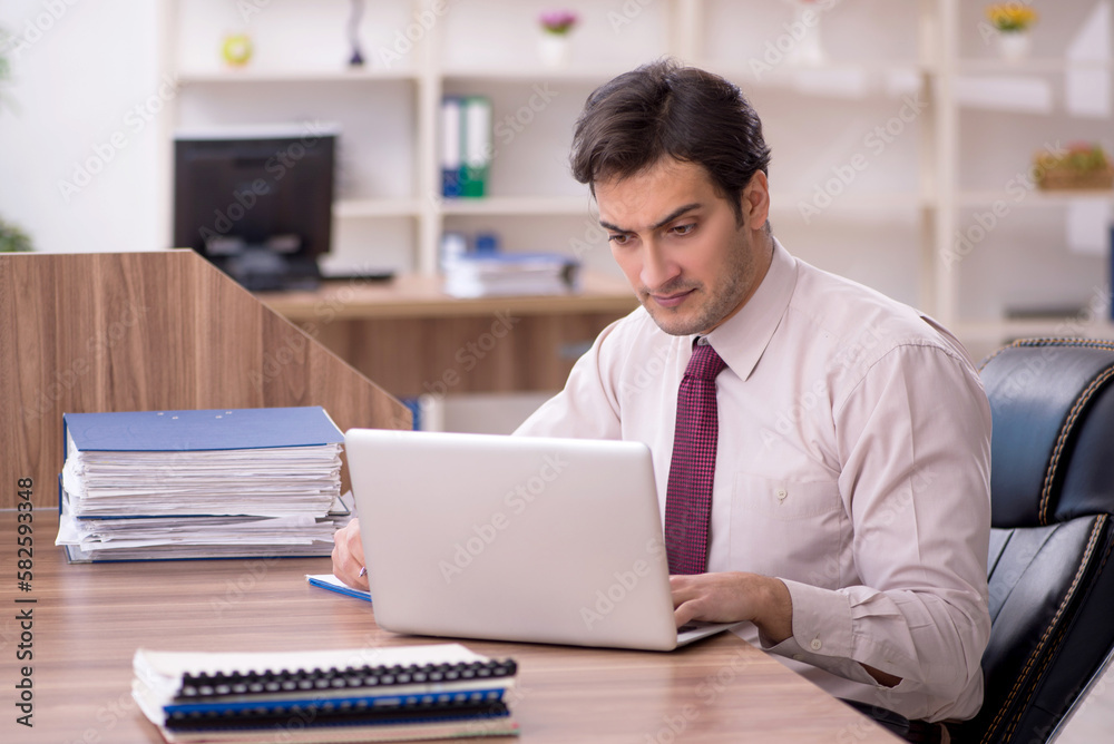 Young male employee and too much work in the office Young male employee and too much work in the office