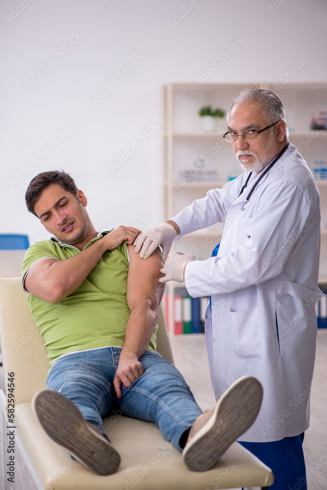 Obraz premium Young male patient visiting old male doctor in vaccination conce