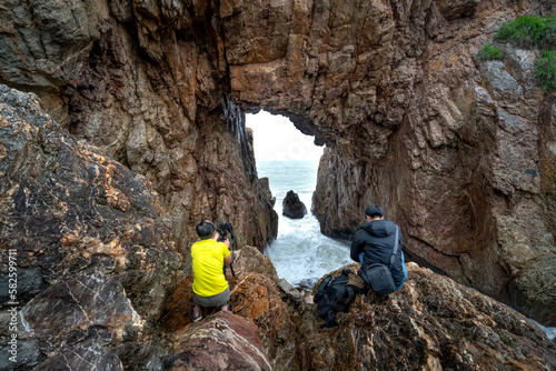 Tourists enjoy the experience at "Mui Vi Rong" with a rock cave connecting to the sea, a wild beauty in Tan Phung Fishing Village, Phu My, Binh Dinh, Vietnam 