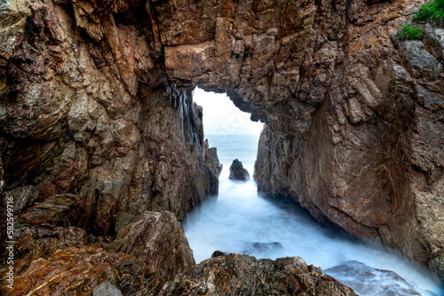 Tourists enjoy the experience at "Mui Vi Rong" with a rock cave connecting to the sea, a wild beauty in Tan Phung Fishing Village, Phu My, Binh Dinh, Vietnam 