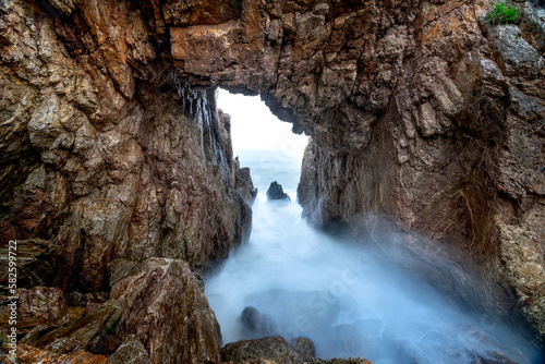 Tourists enjoy the experience at "Mui Vi Rong" with a rock cave connecting to the sea, a wild beauty in Tan Phung Fishing Village, Phu My, Binh Dinh, Vietnam 