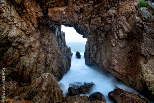 Tourists enjoy the experience at "Mui Vi Rong" with a rock cave connecting to the sea, a wild beauty in Tan Phung Fishing Village, Phu My, Binh Dinh, Vietnam 