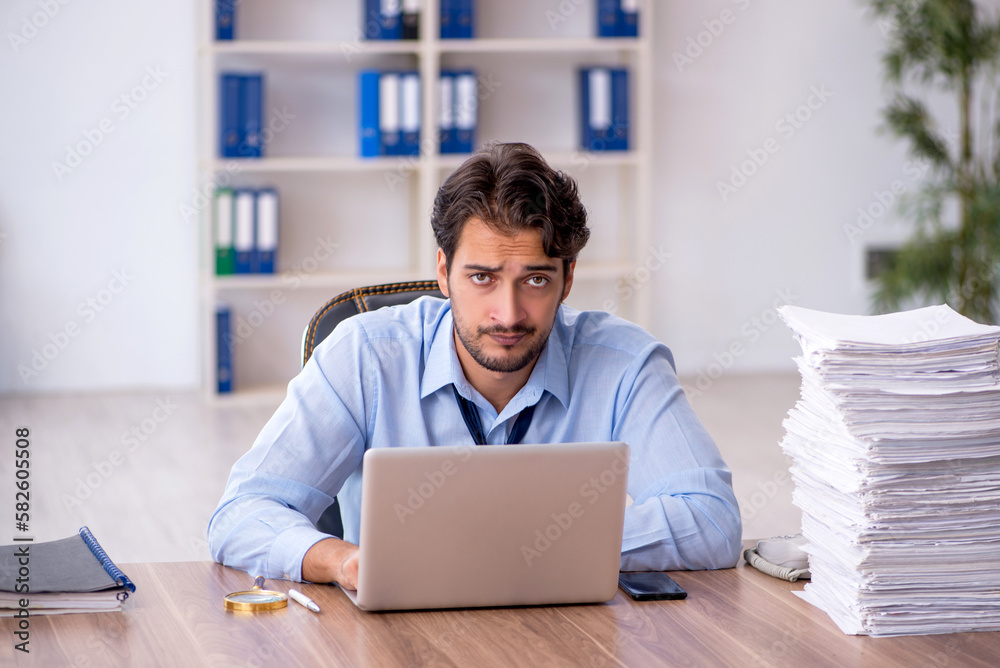 Young male employee and too much work in the office Young male employee and too much work in the office