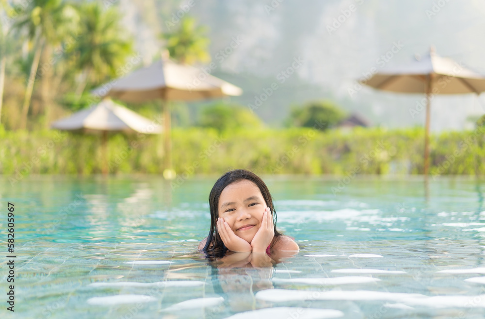 Asian child summer or kid girl happy smile lying down relax on swimming pool in water park or person learning swim to sports exercise on nature green field for holiday vacation travel at krabi hotel