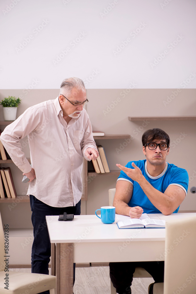 Obraz premium Young male student and his grandfather at home