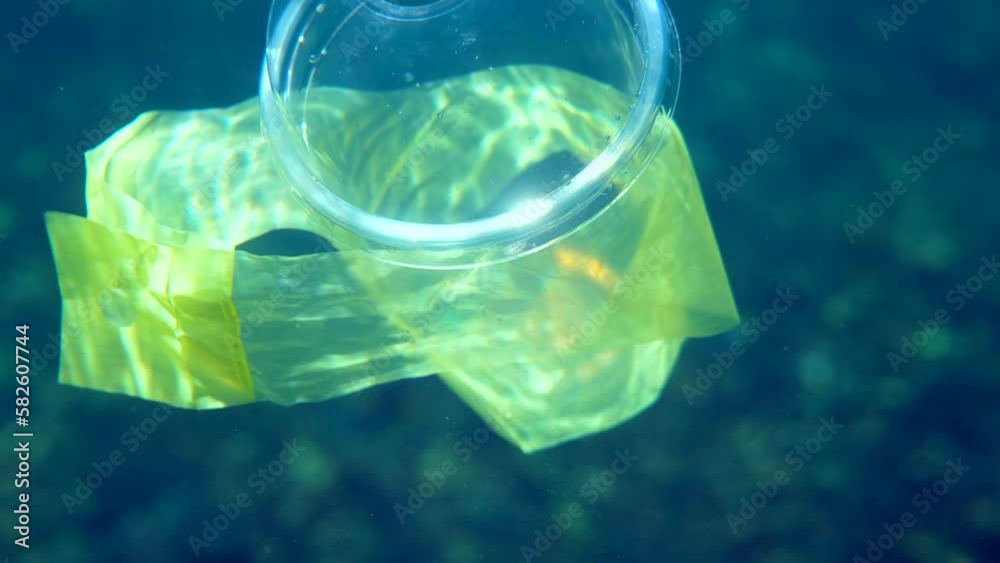 Video Stock Plastic bag and cup floating in the ocean water with a fish and coral reef in