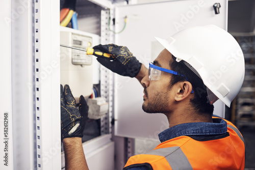 Man, electricity and screwdriver of maintenance box in control room, engineering or machine mechanic. Male electrician, screw tool and power installation of industrial generator, technician or repair photo