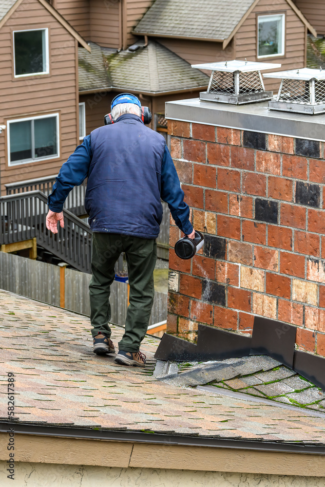 Senior man with a container of moss killer spreading the granules on a