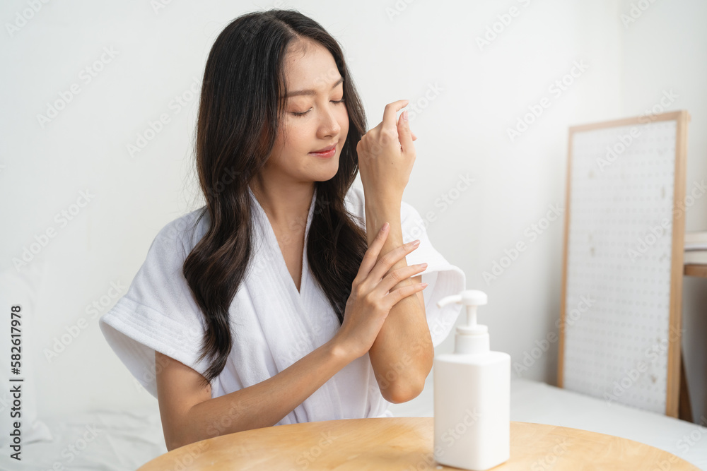 Young woman applying moisturizer cream to her arm in the morning routine. Young woman applying moisturizer cream to her arm in the morning routine.