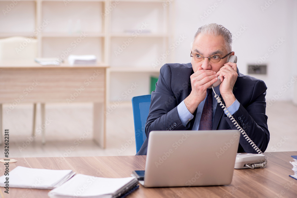 Old male employee working in the office