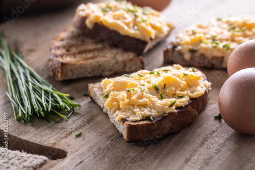 Foto Fresh scrambled eggs spread on a slice of bread with whole eggs and fresh chive