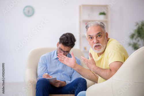 Old man visiting young male psychotherapist