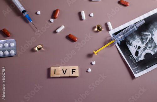 The abbreviation ECO is lined with wooden letters on a pink background. In vitro injection pen, tablets. Syringe with thin huge. ECO concept. Infertility. Ultrasound. Hormonal drugs for stimulation