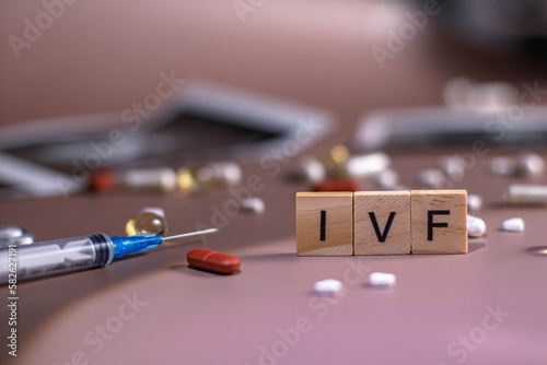 The abbreviation ECO is lined with wooden letters on a pink background. In vitro injection pen, tablets. Syringe with thin huge. ECO concept. Infertility. Ultrasound. Hormonal drugs for stimulation
