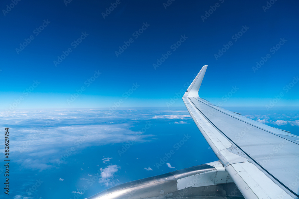 Obraz premium View of the blue sky and fluffy clouds from the window of the plane.