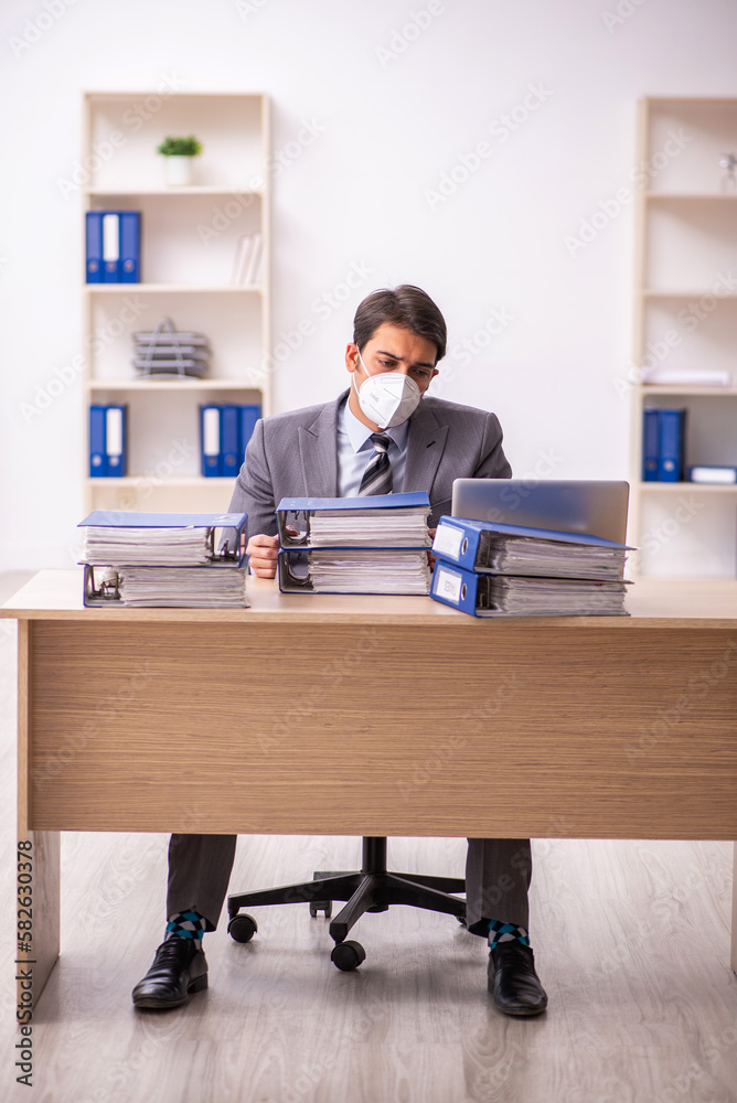 Young male employee working at workplace during pandemic Young male employee working at workplace during pandemic