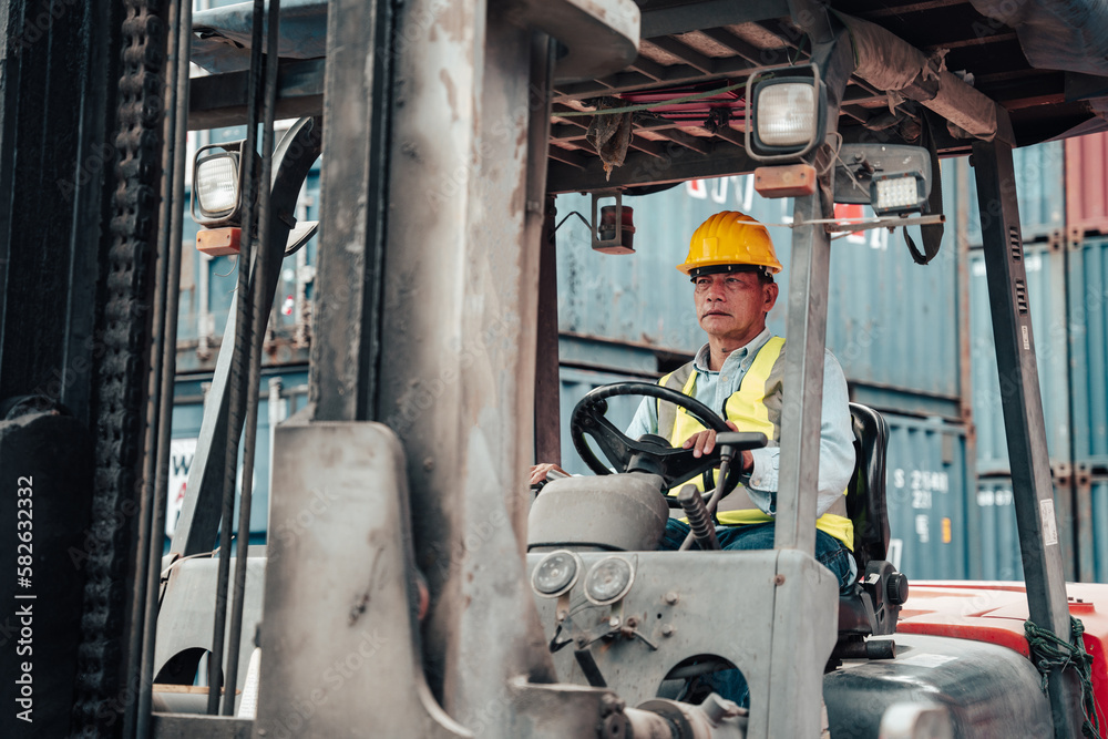Male worker wearing a helmet drives a forklift inspecting containers. Male worker wearing a helmet drives a forklift inspecting containers.