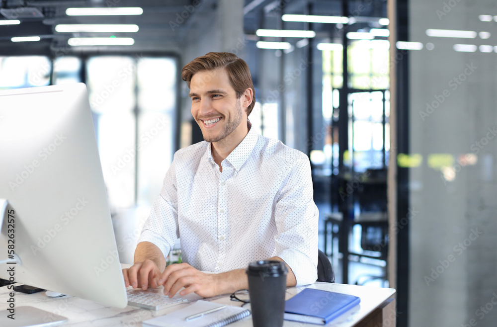 Young modern business man working using computer while sitting in the office. Young modern business man working using computer while sitting in the office.