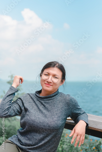 Beautiful asian woman (LGBTQ) natural makeup wear fashion relax clothes posing at sea viewpoint with happy and fun emotion in concept travel, vacation, leisure in life