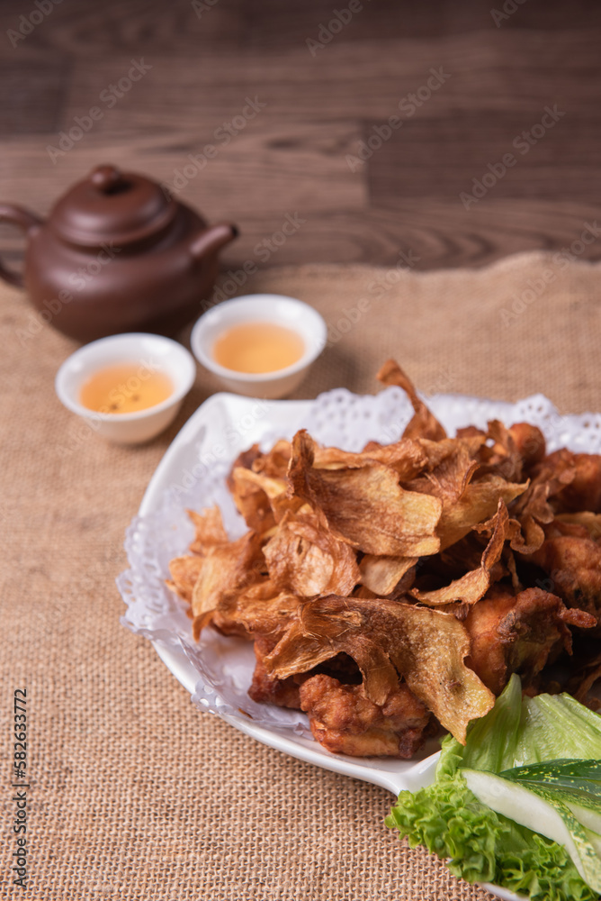 Fototapeta premium deep fried crispy golden chicken meat with ginger slices and garlic on wood table chinese tea pot asian halal banquet menu