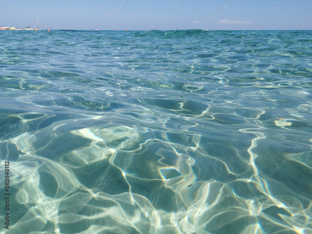 Crystal clear, blue, transparent water of the Mediterranean Sea on Sunrise beach.