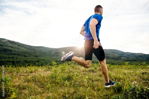 back male runner running colorful mountain plateau, summer sunset, sports photo
