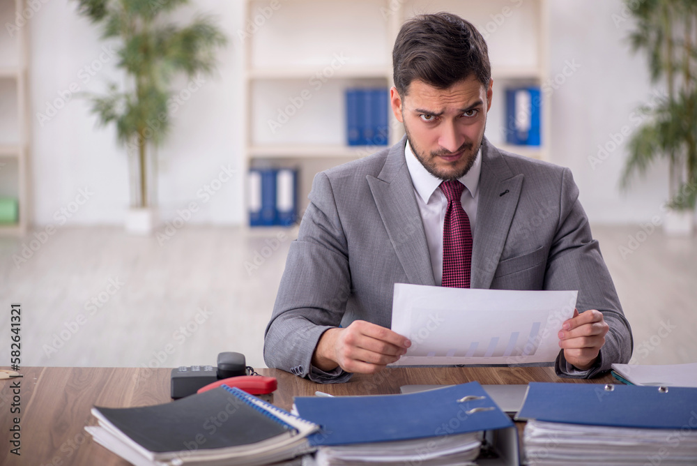 Young male employee and too much work in the office