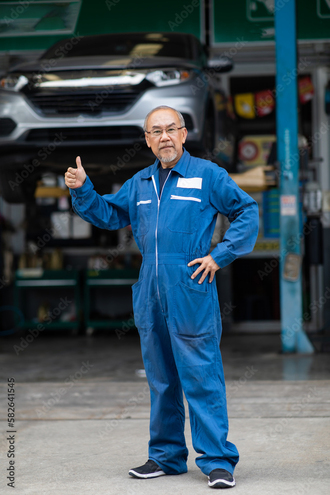 Portrait of a Asian senior mechanic working in his car service garage. Car maintenance and auto service garage concept. Portrait of a Asian senior mechanic working in his car service garage. Car maintenance and auto service garage concept.