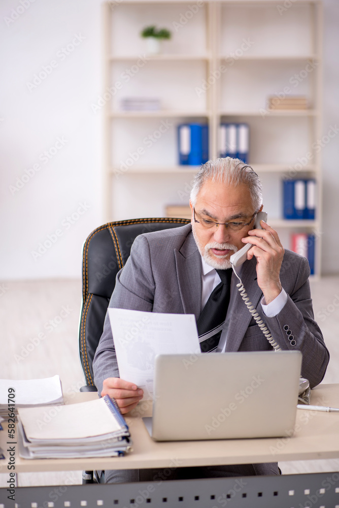 Old male employee working in the office Old male employee working in the office