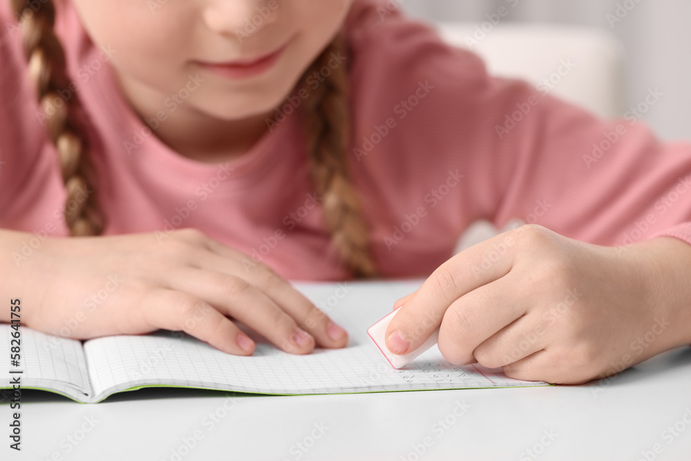 Girl using eraser at white desk, closeup Girl using eraser at white desk, closeup