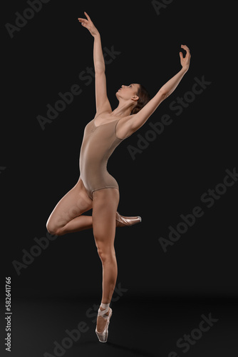 Young ballerina in pointe shoes dancing on black background © New Africa