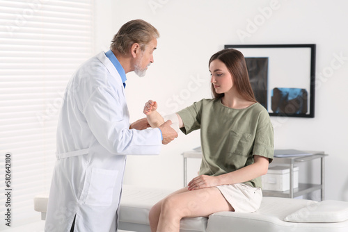 Orthopedist applying bandage onto patient s elbow in clinic