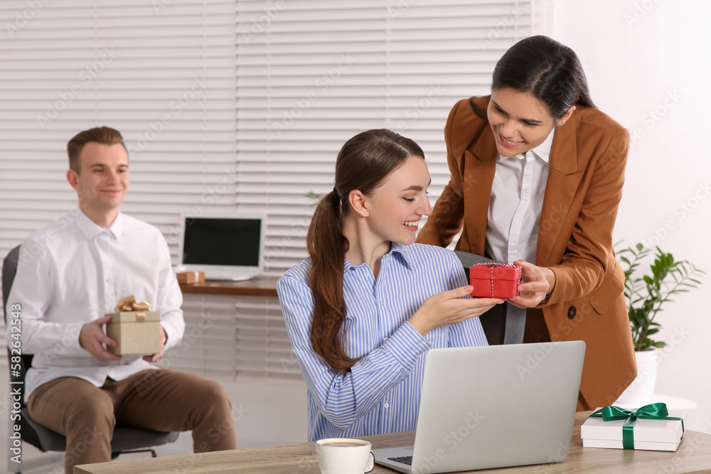 Woman presenting gift to her colleague in office