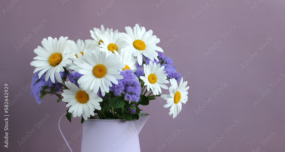 floral background, daisies and ageratum in a jug on a lilac backdrop. garden flowers.