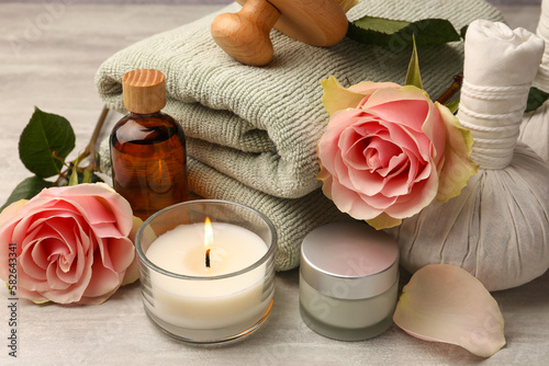 Composition with spa products, roses and candle on grey wooden table