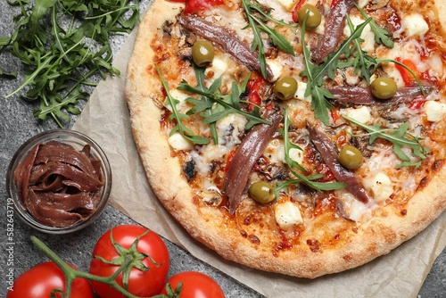 Tasty pizza with anchovies and ingredients on grey table, flat lay