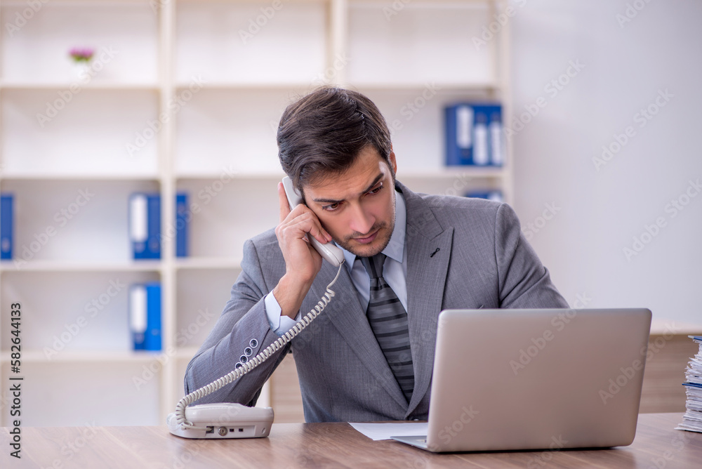 Young male employee unhappy with excessive work in the office Young male employee unhappy with excessive work in the office