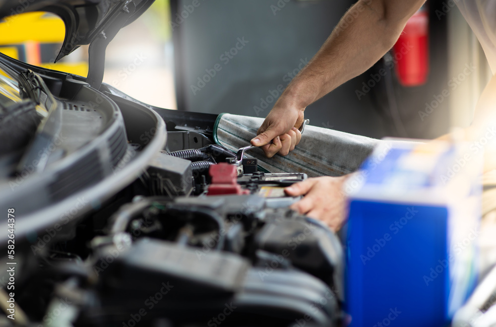 Auto mechanic worker checking and changing car battery. Car maintenance and auto service garage concept. Auto mechanic worker checking and changing car battery. Car maintenance and auto service garage concept.