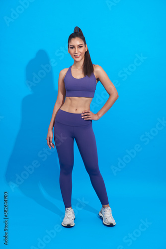 happy asian sporty woman doing sport wearing sportswear over blue background. Healthy and fit strong female concept.
