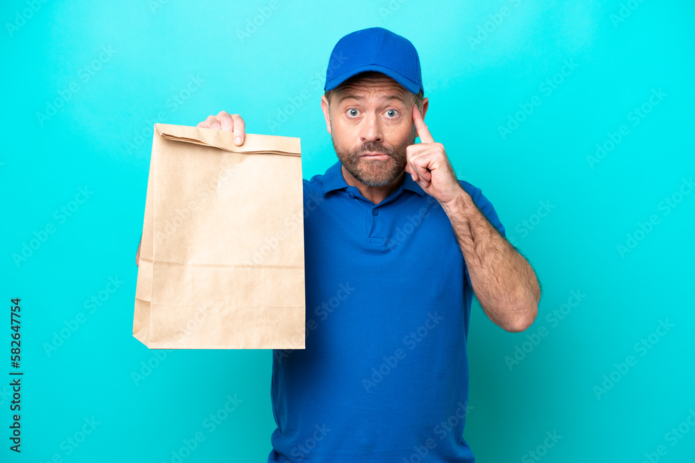 Middle age man taking a bag of takeaway food isolated on blue background thinking an idea