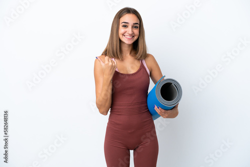 Young sport caucasian woman going to yoga classes isolated on white background pointing to the side to present a product © luismolinero
