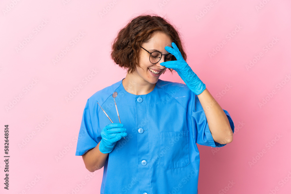 Woman English dentist holding tools over isolated on pink background laughing Woman English dentist holding tools over isolated on pink background laughing