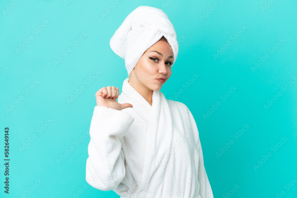 Teenager blonde girl in a bathrobe over isolated blue background proud and self-satisfied Teenager blonde girl in a bathrobe over isolated blue background proud and self-satisfied