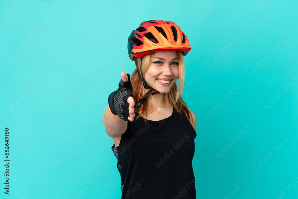 Young cyclist girl over isolated blue background shaking hands for closing a good deal Young cyclist girl over isolated blue background shaking hands for closing a good deal