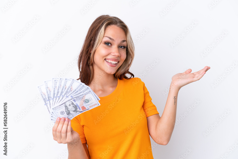 Young Russian girl holding dollars isolated on white background extending hands to the side for inviting to come Young Russian girl holding dollars isolated on white background extending hands to the side for inviting to come