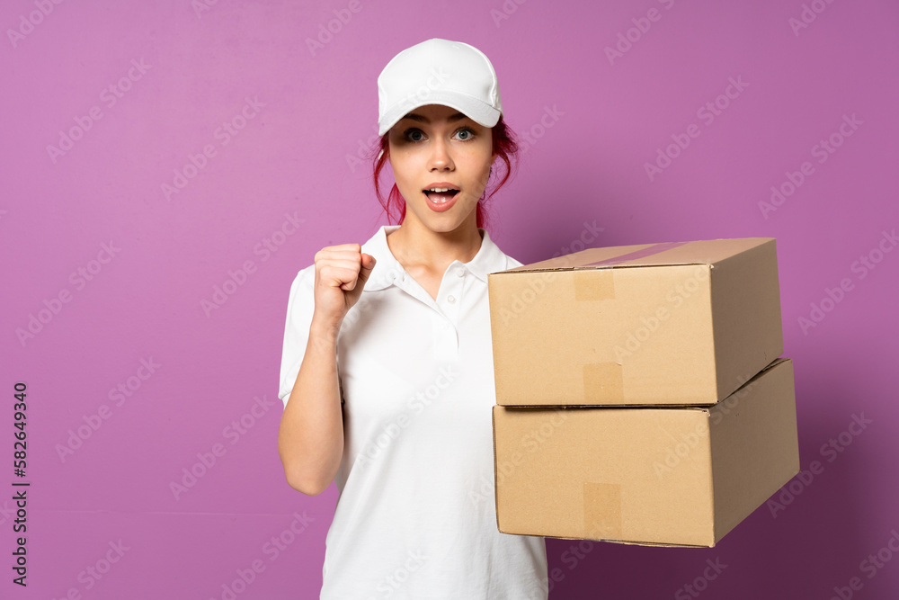 Teenager delivery girl isolated on purple background celebrating a victory in winner position Teenager delivery girl isolated on purple background celebrating a victory in winner position