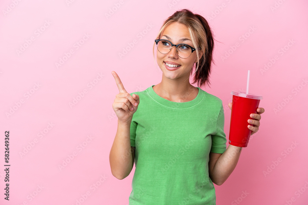 Young Russian woman holding a refreshment isolated on pink background intending to realizes the solution while lifting a finger up Young Russian woman holding a refreshment isolated on pink background intending to realizes the solution while lifting a finger up