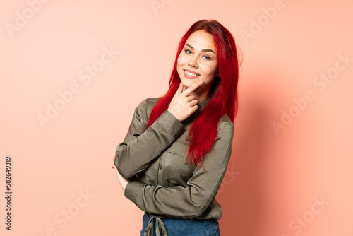 Teenager red hair girl isolated on pink background happy and smiling