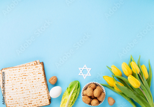 Passover Greeting Card with Matzah, Waluts and Yellow Tulip Flowers on Blue Background.
